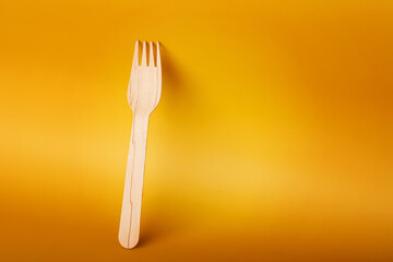 Wooden fork on yellow background. Eco-friendly bamboo cutlery.