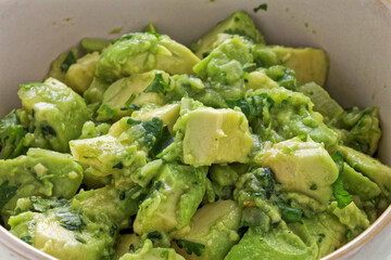 Close-up view of chunky guacamole in ceramic bowl. Mexican cuisine.