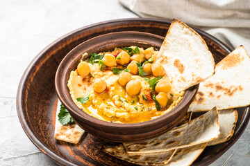 Hummus with olive oil and paprika at light kitchen table.