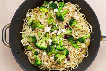 Spaghetti pasta with broccoli vegetable, olives and cheese on big pan top view.