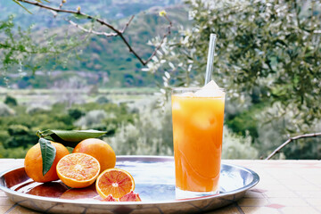 Summer orange cocktail. Fresh healthy citrus juce with ice and ripe bio citrus fuits on steel tray on the table in nature background. Organic Sicilian oranges.