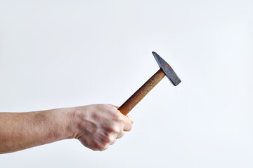 Old hammer in a man's hand on a light background