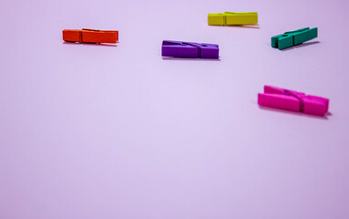 multi-colored clothespins on a pink background in minimalist style