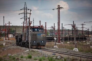 Rudny/Kazakhstan - May 14 2012: Open-pit mining iron ore. Railway train and diesel locomotive on rails in quarry. Blue sky with clouds.	