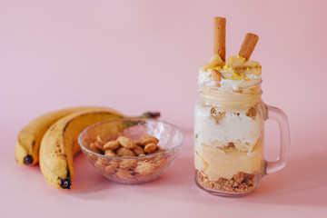 Delicate creamy banana dessert in a glass on a green background.
