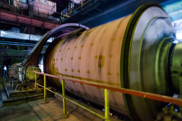 Industrial ball mill on the ore concentration plant. Motion blurred rotated drum.
