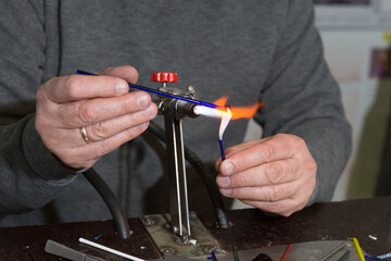 Lampwork. The hands of the master make a glass piece over the burner 