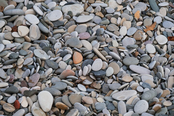 Sea coast view of rocks from above. Minimalistic background. Small sea pebbles. Texture is made of natural stones of different colors and sizes.
