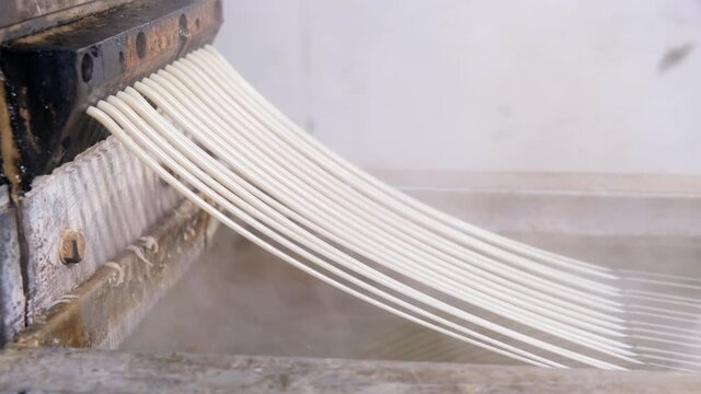 Recycled molten plastic comes out of the extruder machine Concept of recycling, plastic, industry, factories. Continuous extrusion with cooling in water to be processed into a pellet.