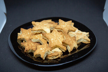 A scary homemade cookie in the shape of stars lies on a black plate. Close-up