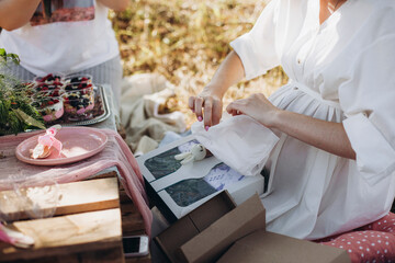 pregnant woman opens a gift. baby shower party. pregnant woman in a white dress on a festive picnic.