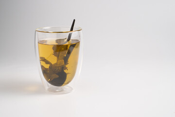 Green tea leaves are brewed in a glass mug. The concept of healthy herbal tea. Background with a cup of tea and copy