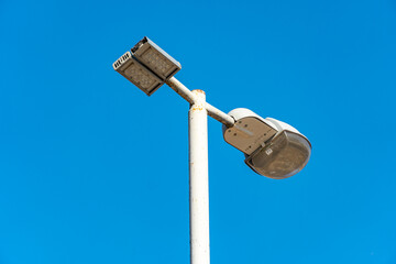 Street lamp on a lamppost against the blue sky, city illumination