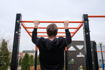 A young man is engaged in a sport on the playground in the park. Fitness, sport, healthy lifestyle