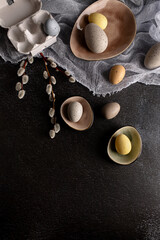 Colourful pastel easter eggs in the nest on a dark background with rustic kitchen decor and paper box