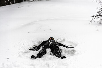 Person on the ground in the snow making a snow angel.
