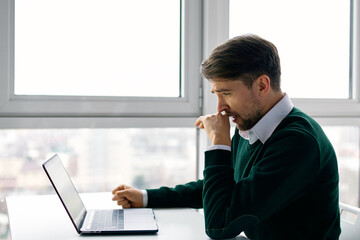 business man sitting at his desk in front of a laptop work is the internet