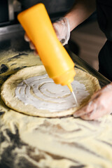 selective focus on pizza base with applied white sauce. pizza making process
