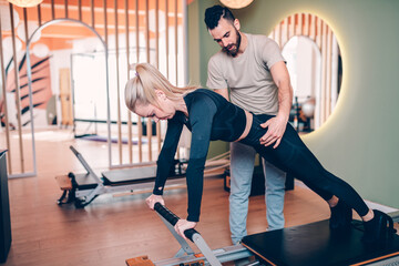 Pilates aerobic male instructor showing exercises to a beautiful middle aged woman. Healthy lifestyle concept.