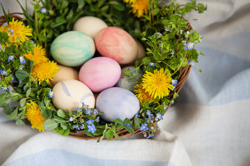 Obraz na płótnie Canvas A beautiful spring bouquet in a wooden basket with Easter eggs painted with watercolors.