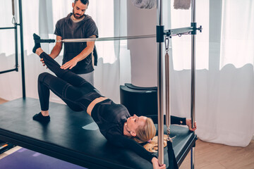 Pilates aerobic male instructor showing exercises to a beautiful middle aged woman. Healthy lifestyle concept.