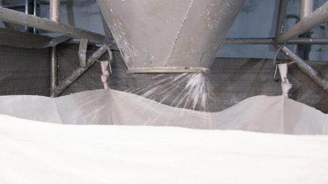 White hard grinded plastic comes out of the cyclone of the machine by pneumatic transport into the big bag. concept of recyclable materials, plastic recycling, pellet production plants