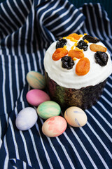 Easter eggs decorated with watercolors and Easter cake lie on a striped blue apron. Easter religious holiday concept.