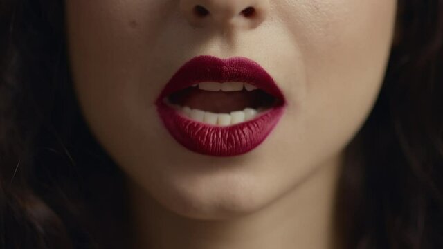 Close up of unrecognizable girl face licking red plump lip with tongue.