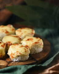 baked rolls with mozzarella and parmesan cheese cap on a wooden board decorated with bamboo leaves