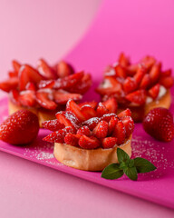 French pastries - a tart consisting of a fruit filling and a crispy baked base. french dessert on a pink background and a sprig of mint