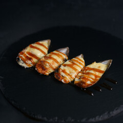 Sea mussels in a shell with unagi sauce on a dark background. gourmet seafood delicacy