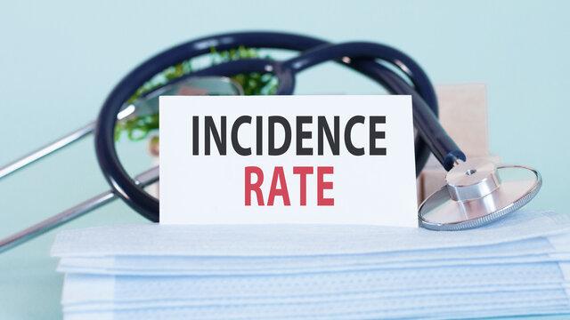 Card with words incidence rate, stethoscope, face masks and flower on table