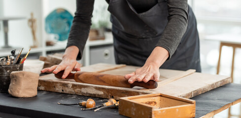 Woman using rolling pin on clay
