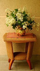 Lush booker of beautiful lilacs in a vase standing on a wicker table