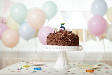 chocolate birthday cake with 5 signs on the cake stand  