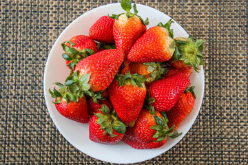 Whole strawberries in white bowl and dark background