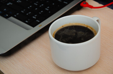 Notepad, laptop and coffee cup on wood table. View from above