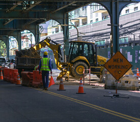 Street construction zone, sign men working with people and heavy machines in the background