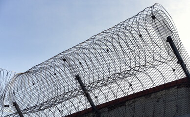 Mauer mit Stacheldraht vor trostlos grauem Himmel