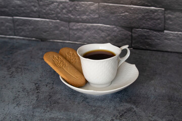 cup of coffee on the table with biscuits cookies black bricks background