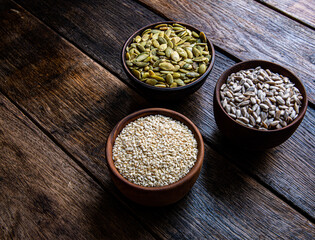 Peeled pumpkin, sunflower and sesame seeds in a wooden bowl on a wooden table. Bakery ingredients. Products for tasty and healthy food.