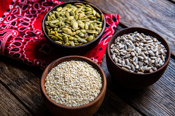 Заголовок: Peeled pumpkin, sunflower and sesame seeds in a wooden bowl on a wooden table. Bakery ingredients. Products for tasty and healthy food.