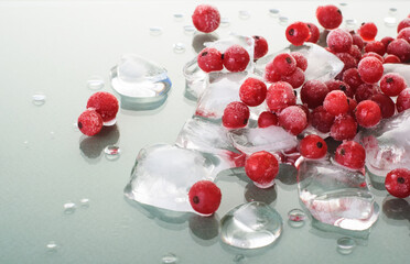 frozen red currants and ice cubes on green glossy background.juicy frozen red berries