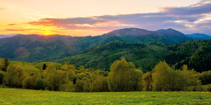 rolling rural mountain landscape at dusk. gorgeous nature scenery in spring. clouds on the sky in evening light