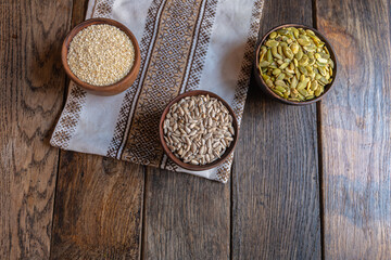 Peeled pumpkin, sunflower and sesame seeds in a wooden bowl on a wooden table. Bakery ingredients. Products for tasty and healthy food.