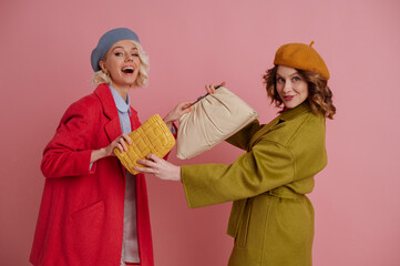 Funny fashionable girls fight for trendy leather bags. Models wearing stylish spring coats, berets. Shopping, fashion, sale, discount conception. Copy, empty space for text