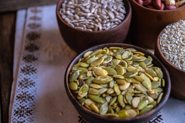 Peeled pumpkin, sunflower, nut, and sesame seeds in a wooden bowl on a wooden table. Bakery ingredients. Products for tasty and healthy food.