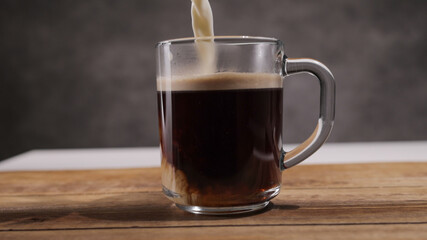Pour milk into a freshly brewed cup of coffee - studio photography