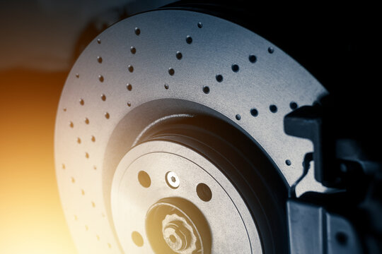 Installation of new perforated brake discs and pads on a modern auto in a car workshop. Close up. Blur effect.