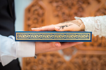 Muslim wedding ceremony bride and groom holding together a Quran take an oath of allegiance.
